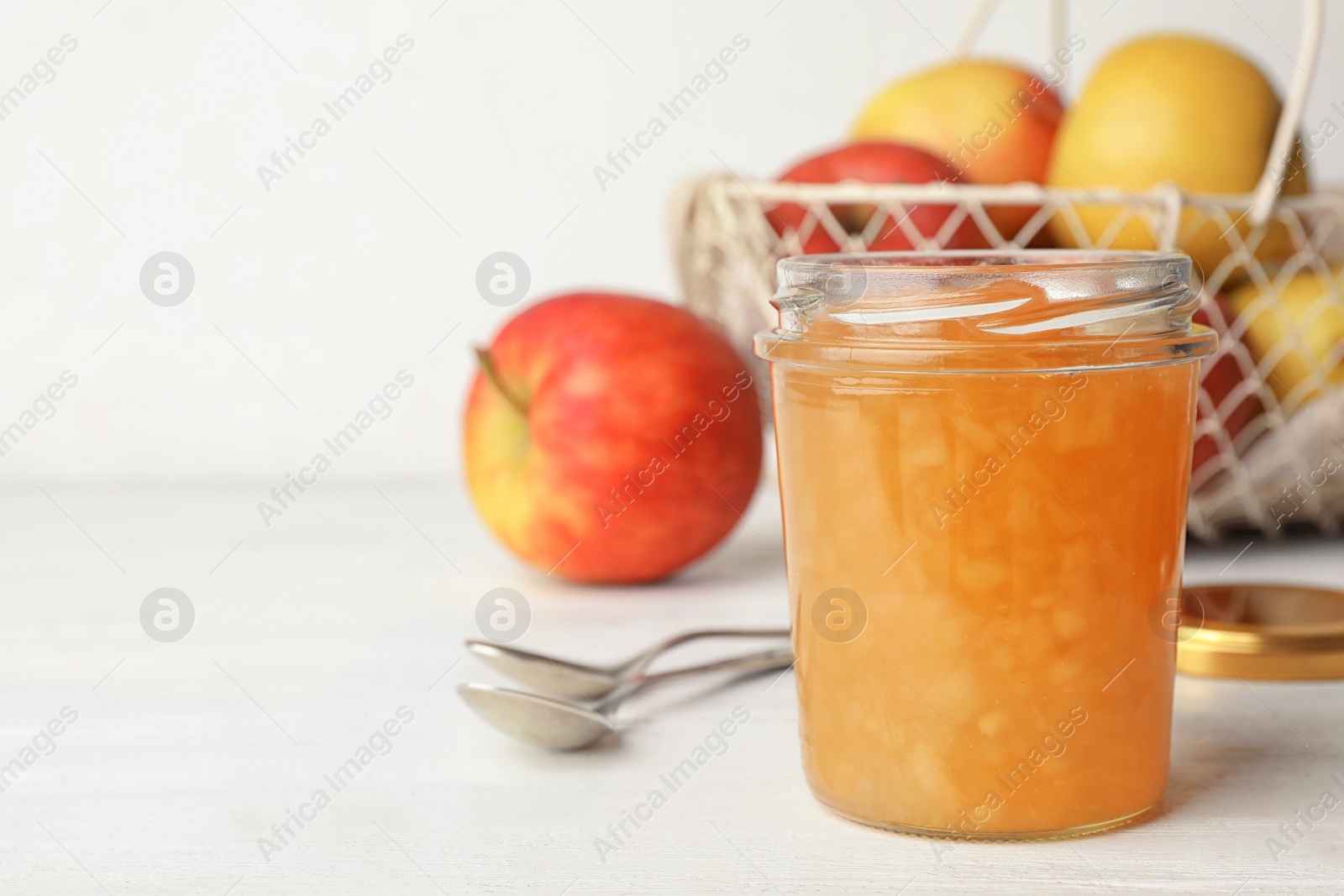 Photo of Homemade delicious apple jam on white wooden table. Space for text