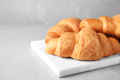 Tasty fresh croissants on light grey table, closeup