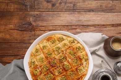 Photo of Delicious sweet baklava with coffee on wooden table, flat lay. Space for text