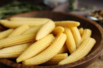 Photo of Fresh baby corn cobs in wooden bowl, closeup