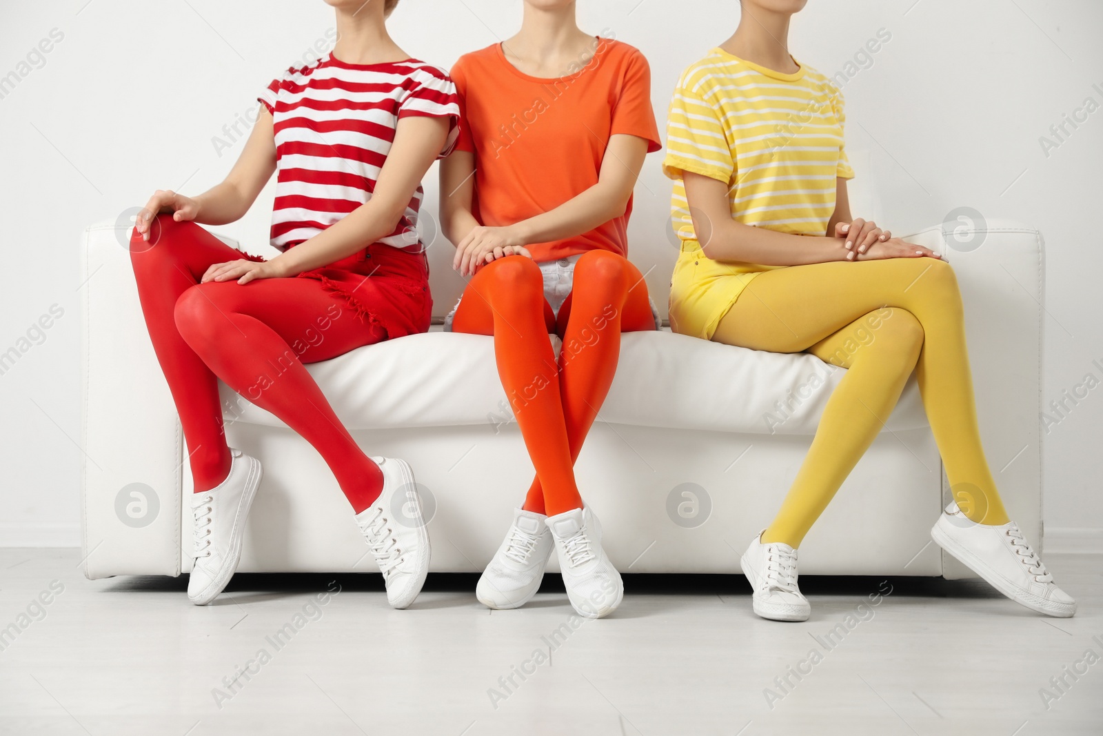 Photo of Women wearing bright tights sitting on sofa indoors, closeup