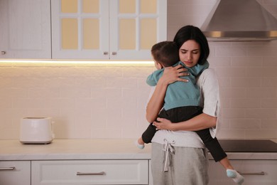Photo of Depressed single mother with child in kitchen, space for text