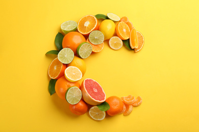 Photo of Letter C made with citrus fruits on yellow background as vitamin representation, flat lay