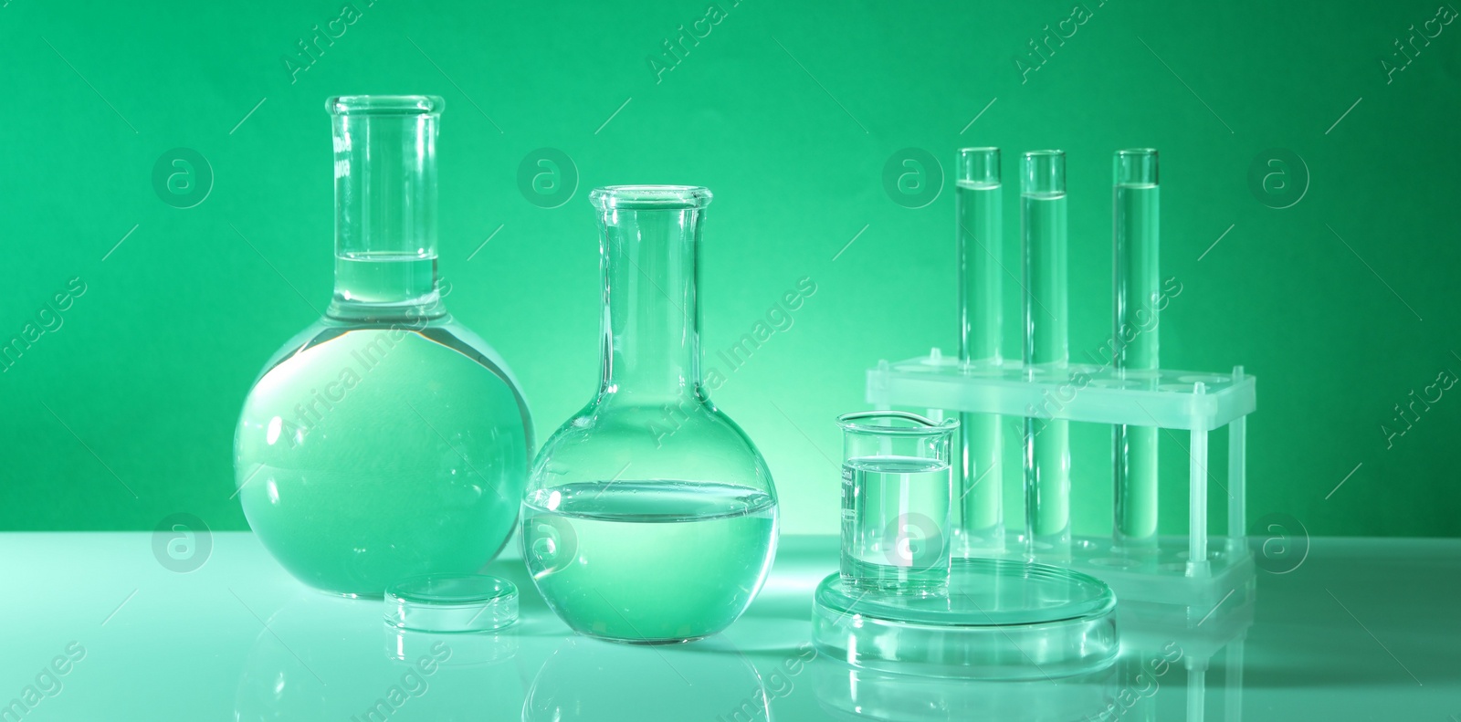 Photo of Laboratory analysis. Different glassware on table against green background