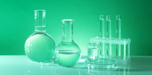 Laboratory analysis. Different glassware on table against green background