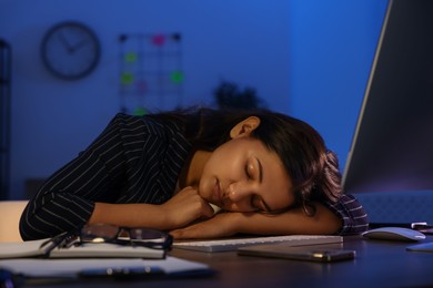 Photo of Tired overworked businesswoman napping at night in office