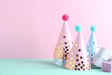 Photo of Party hats and gift boxes on color background, space for text