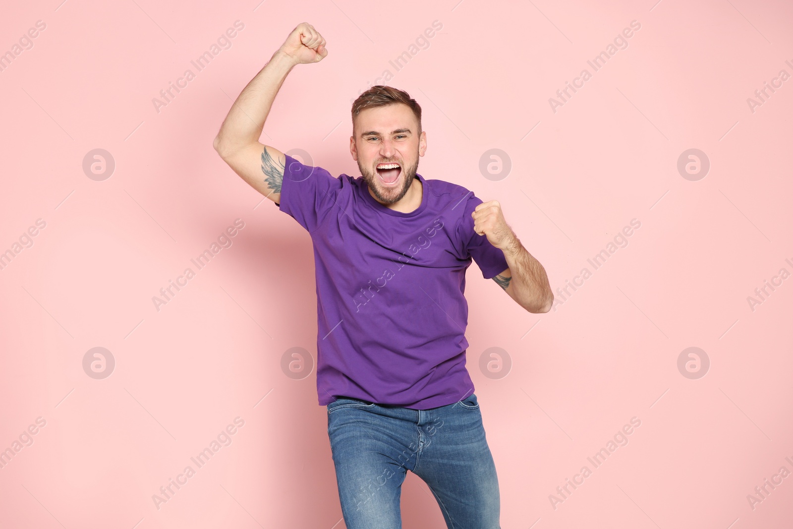 Photo of Young man celebrating victory on color background