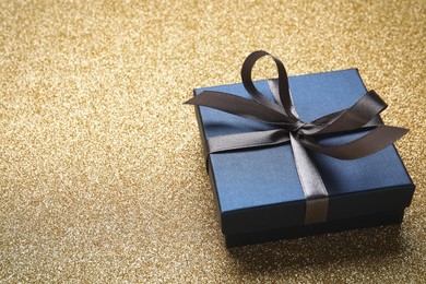 Photo of Blue gift box on golden background. Space for text