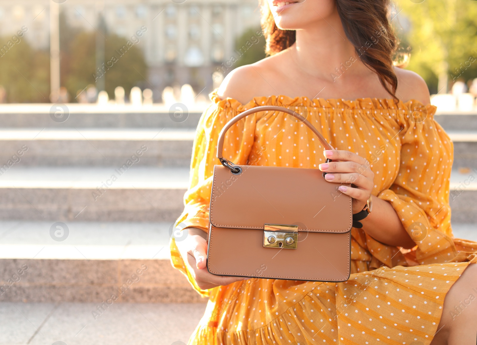 Photo of Young woman with stylish brown bag on stairs outdoors, closeup