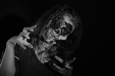 Scary zombie on dark background, black and white effect. Halloween monster