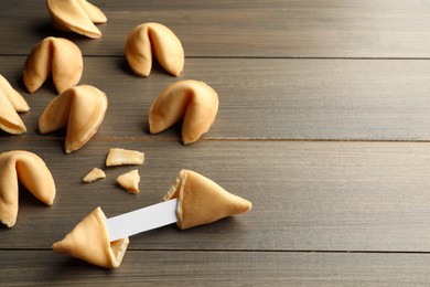 Tasty fortune cookies with predictions on wooden table, space for text