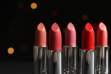 Photo of Different lipsticks against blurred lights. Cosmetic product