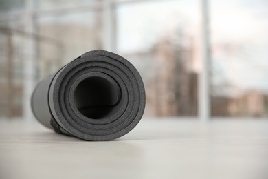 Photo of Rolled grey yoga mat on floor indoors