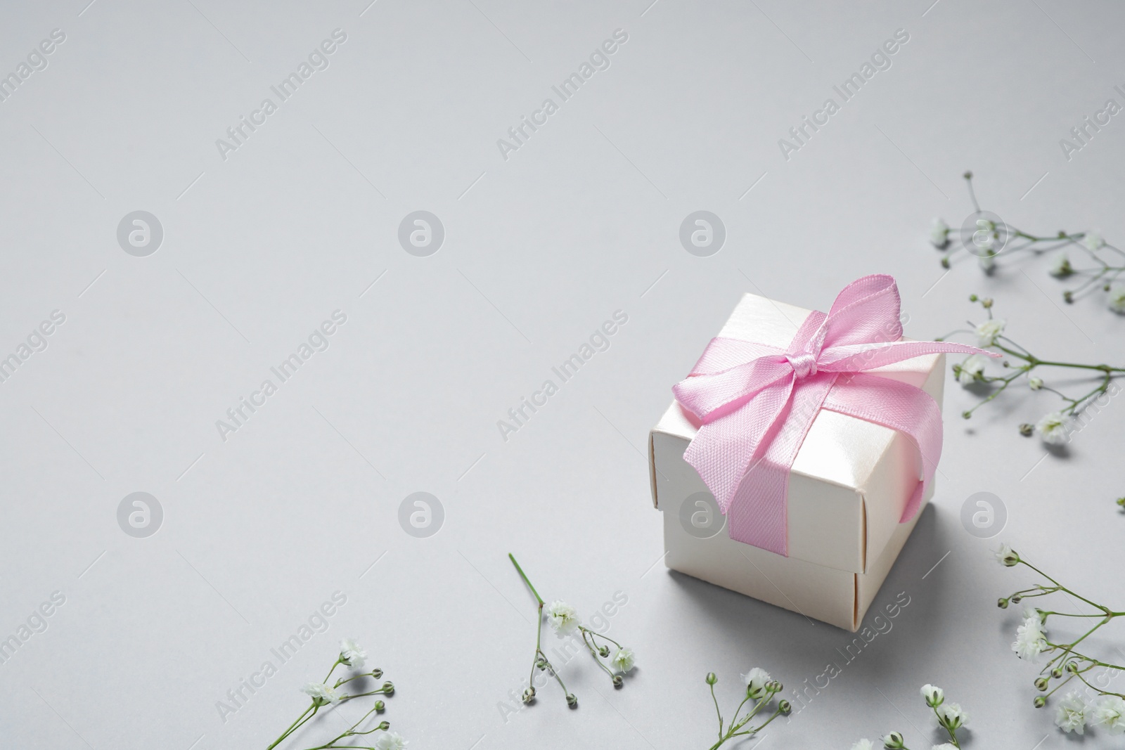 Photo of Gift box and flowers on grey background, space for text. Happy Mother's Day