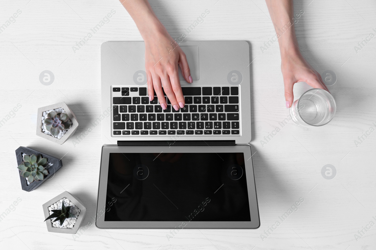 Photo of Woman using laptop at white wooden table, closeup of hands. Space for text