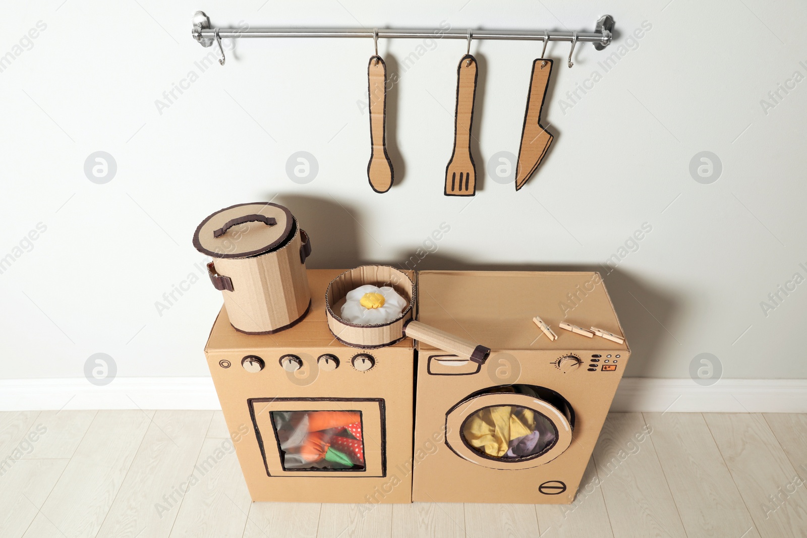 Photo of Cardboard kitchen and washing machine near white wall indoors