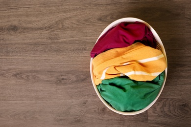 Laundry basket with dirty clothes on wooden background, top view. Space for text