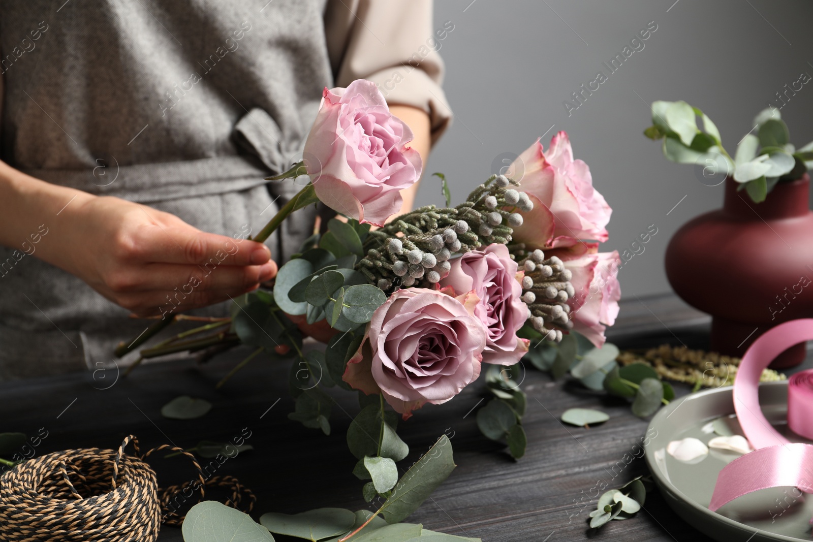 Photo of Florist creating beautiful bouquet at black wooden table indoors, closeup