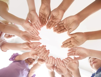 Photo of Little children putting their hands together indoors, view from below. Unity concept