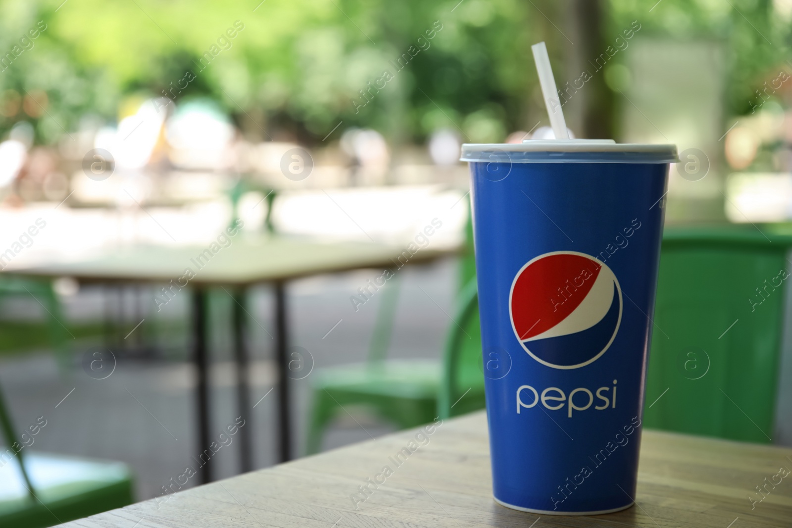 Photo of MYKOLAIV, UKRAINE - JUNE 9, 2021: Paper Pepsi cup on wooden table outdoors, space for text