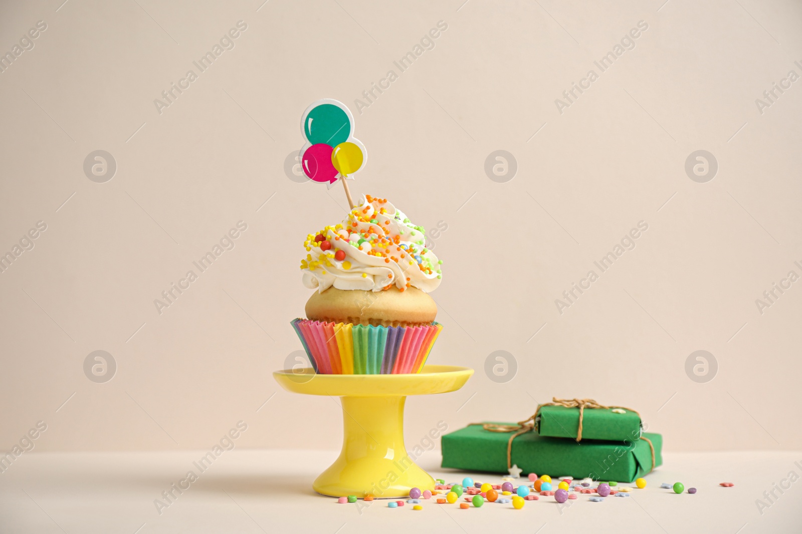 Photo of Birthday cupcake and gift boxes on beige background