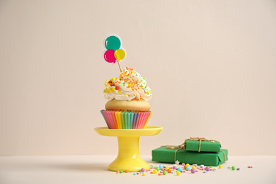 Photo of Birthday cupcake and gift boxes on beige background