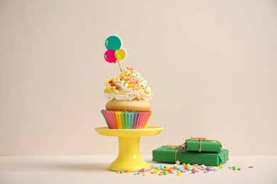 Birthday cupcake and gift boxes on beige background