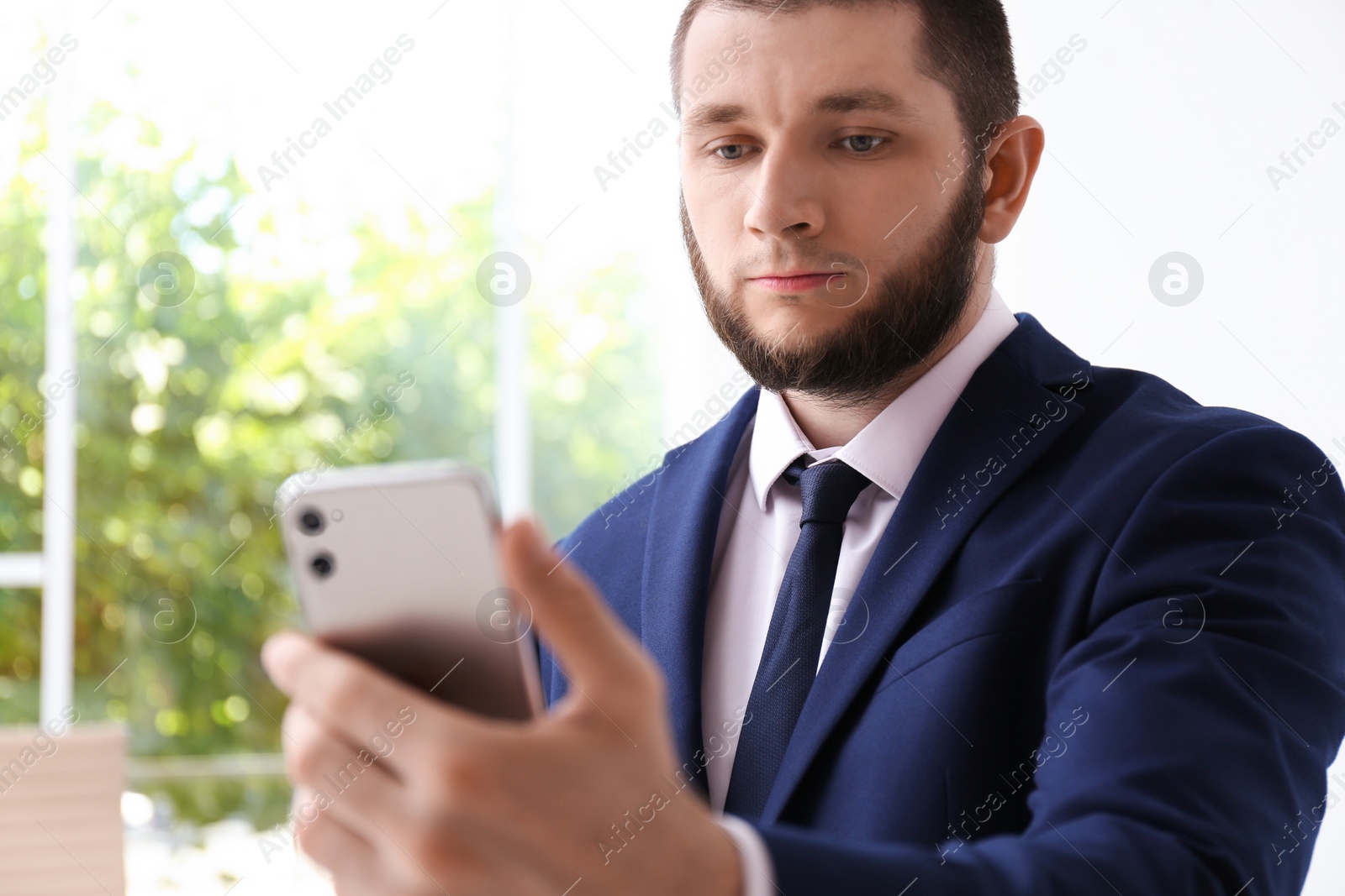 Photo of Man unlocking smartphone with facial scanner indoors. Biometric verification