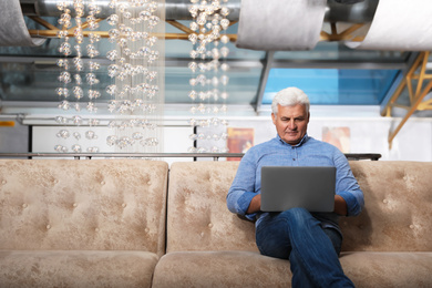 Photo of Senior business owner working with laptop in his restaurant