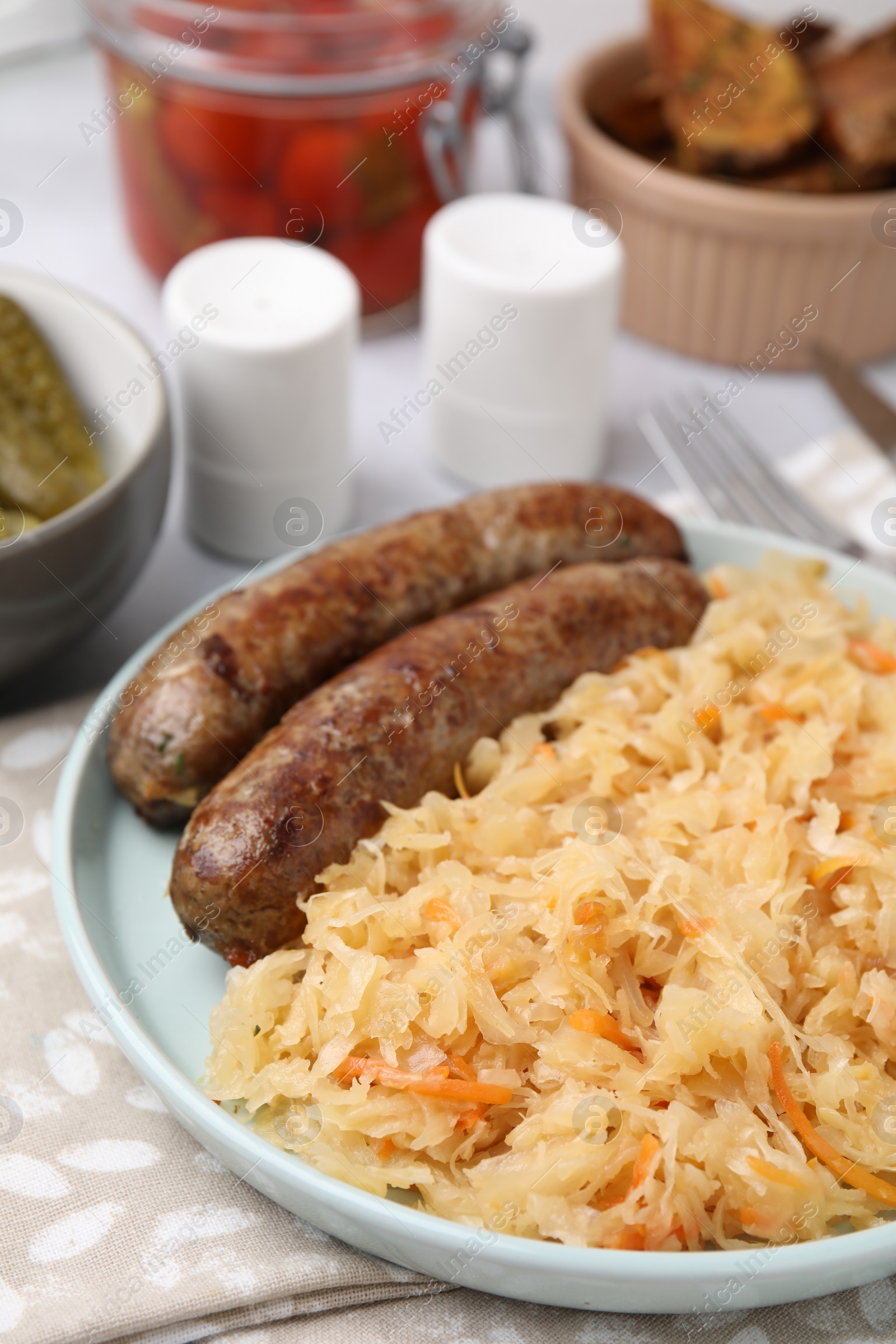 Photo of Plate with sauerkraut and sausages on table, closeup