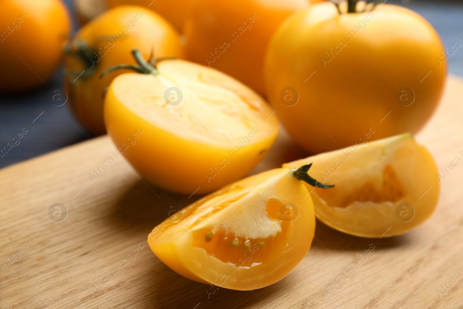 Photo of Ripe yellow tomatoes on wooden board, closeup