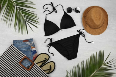 Photo of Flat lay composition with black swimsuit and beach accessories on grey marble background
