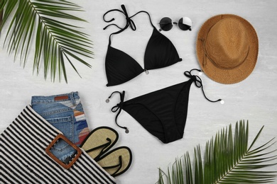 Flat lay composition with black swimsuit and beach accessories on grey marble background