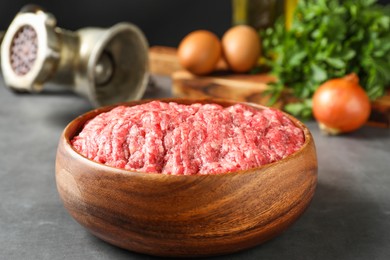 Photo of Raw ground meat in bowl on grey table, closeup