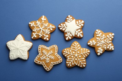 Photo of Tasty star shaped Christmas cookies with icing on blue background, flat lay