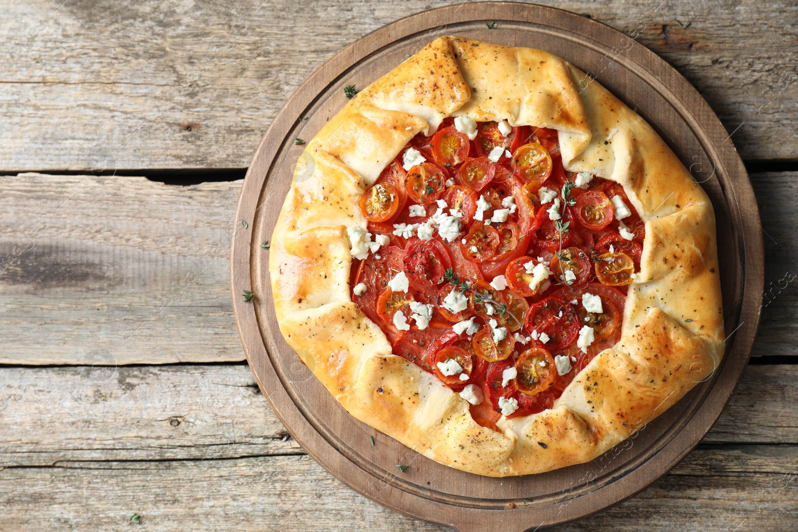 Photo of Tasty galette with tomato, thyme and cheese (Caprese galette) on wooden table, top view. Space for text