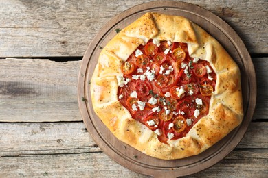 Tasty galette with tomato, thyme and cheese (Caprese galette) on wooden table, top view. Space for text