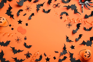 Photo of Frame made with Halloween decor elements on orange background, flat lay. Space for text