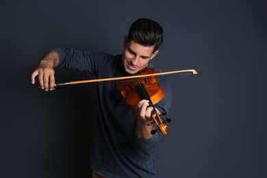 Happy man playing violin on black background