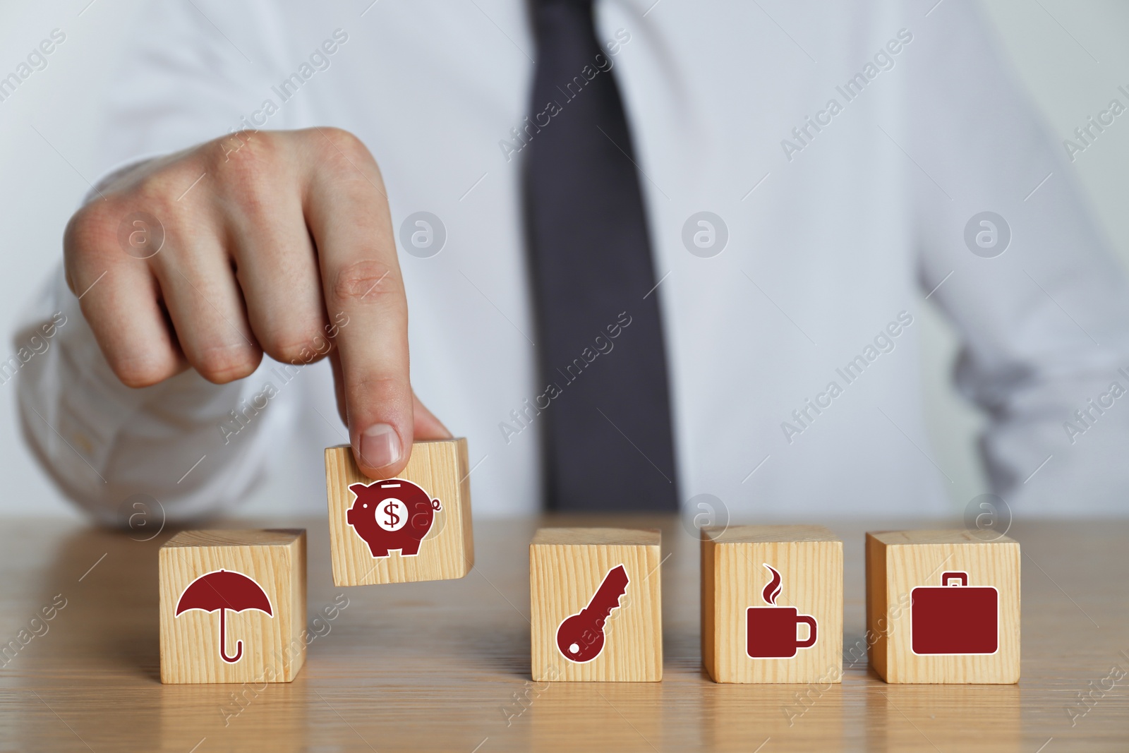 Image of Man and wooden cubes with different icons on wooden table, closeup. Insurance concept