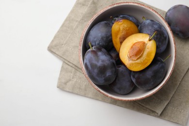 Tasty ripe plums on white table, flat lay. Space for text