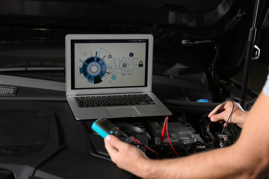 Photo of Mechanic with laptop near auto, closeup. Modern car diagnostic