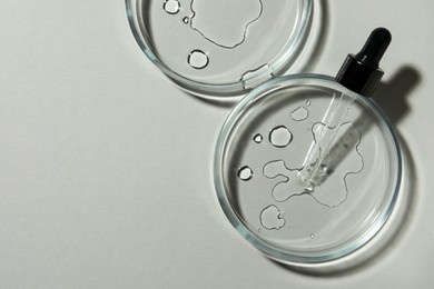 Photo of Petri dishes with sample and pipette on light grey background, flat lay. Space for text