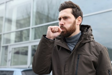 Photo of Sick man coughing on city street. Cold symptoms