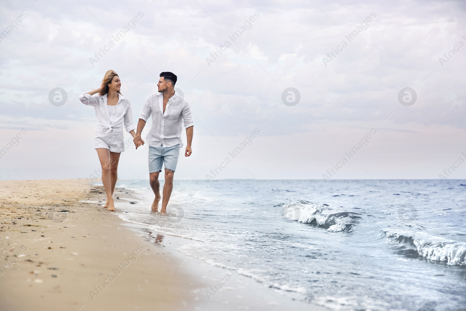 Photo of Happy couple having romantic walk on beach. Space for text