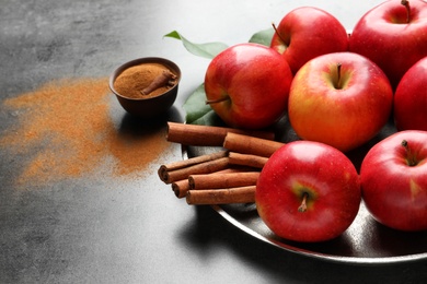 Photo of Fresh apples with cinnamon sticks and powder on gray table