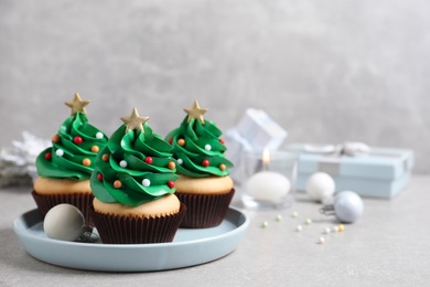 Photo of Christmas tree shaped cupcakes on light grey table. Space for text