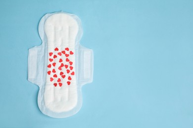 Menstrual pad with confetti on light blue background, top view. Space for text