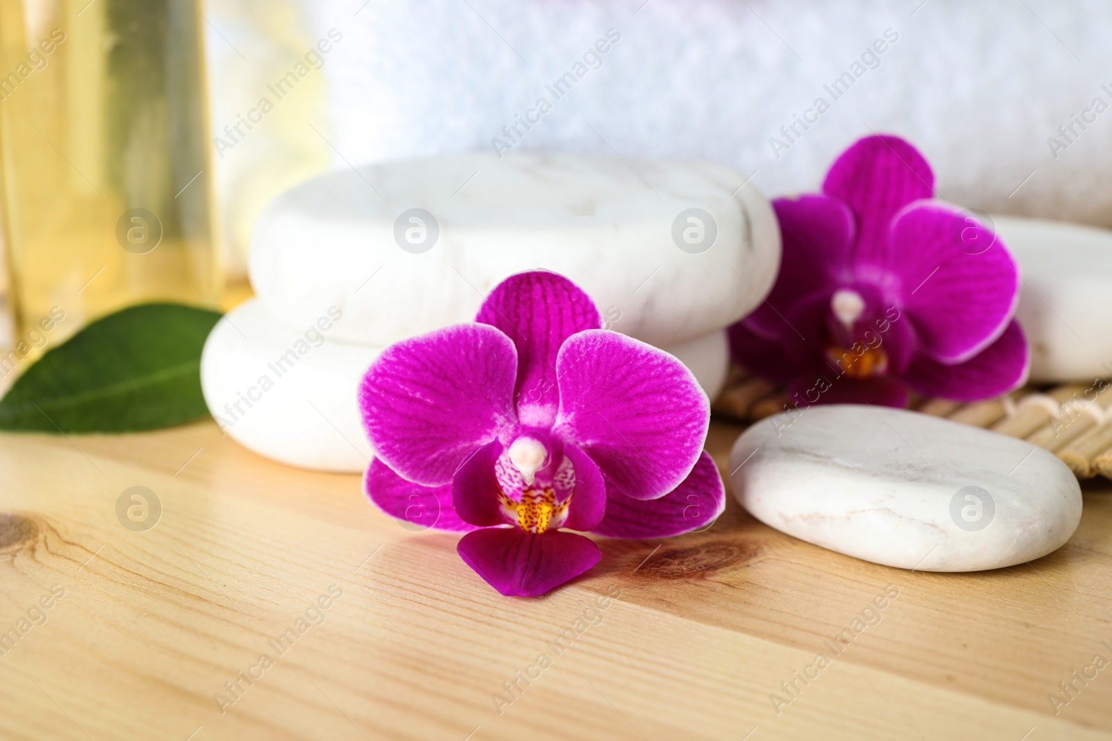 Photo of Spa stones and orchid flowers on wooden table